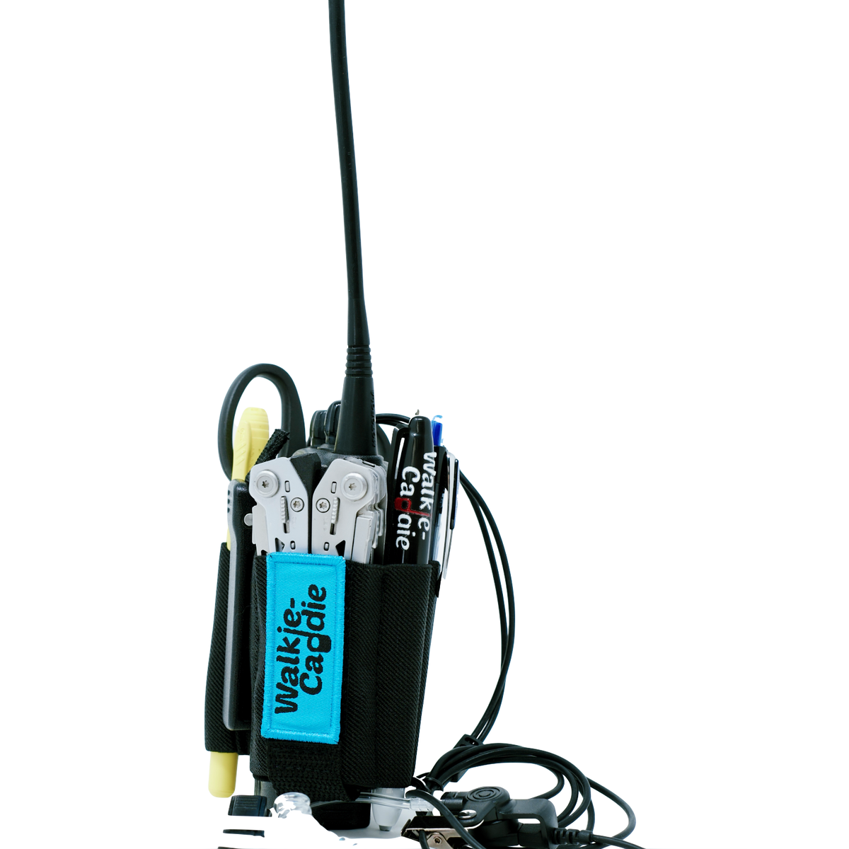 A Walkie Caddie, a multi-tool organizer for a set radio, with a blue Walkie Caddie velcro patch-holding a walkie-talkie, scissors, utility knife, markers, and keys. The organizer features a bright blue label that reads a Walkie Caddle